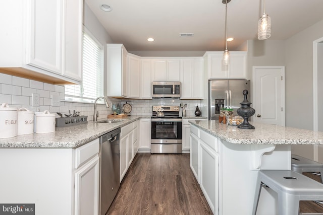 kitchen with pendant lighting, sink, white cabinets, and appliances with stainless steel finishes