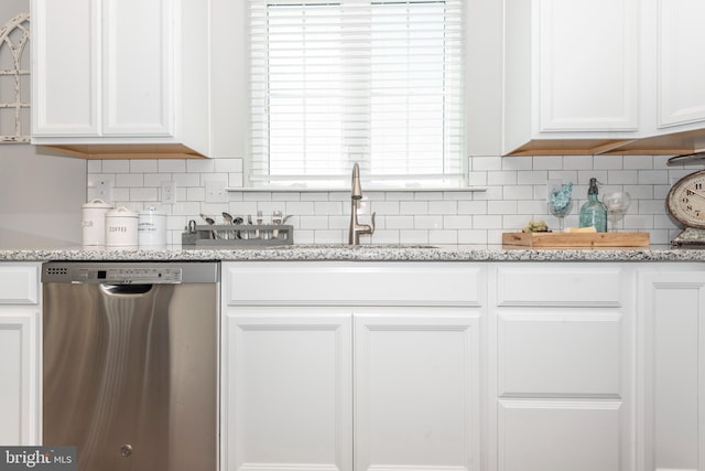 kitchen with light stone countertops, stainless steel dishwasher, sink, and white cabinets