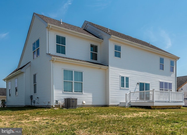 rear view of property featuring central AC unit, a lawn, and a deck