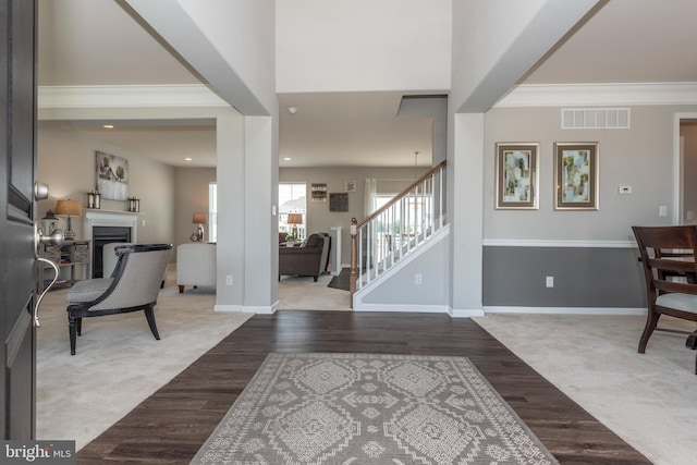 carpeted entrance foyer featuring a towering ceiling and ornamental molding