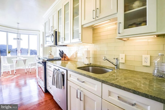 kitchen with pendant lighting, sink, white cabinets, dark stone counters, and stainless steel appliances