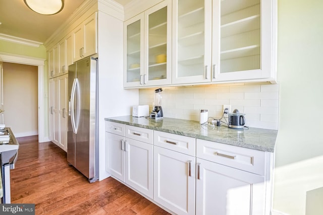 bar featuring tasteful backsplash, white cabinetry, stainless steel fridge, hardwood / wood-style flooring, and light stone counters