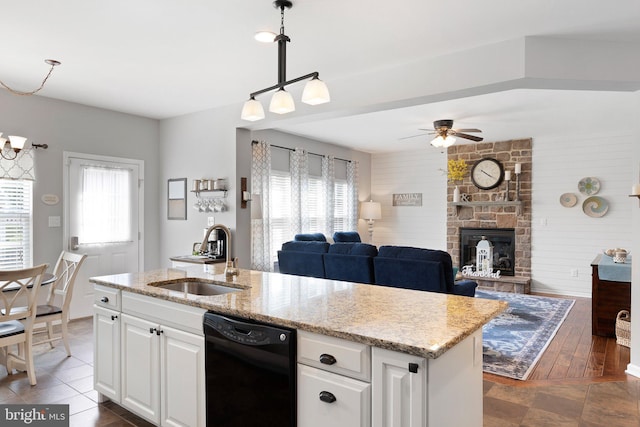 kitchen with dishwasher, sink, white cabinets, hanging light fixtures, and a center island with sink