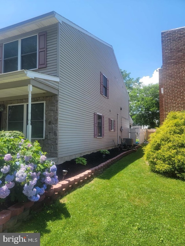 view of side of property with a yard and central AC