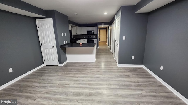 kitchen featuring range, kitchen peninsula, light hardwood / wood-style floors, and white cabinets