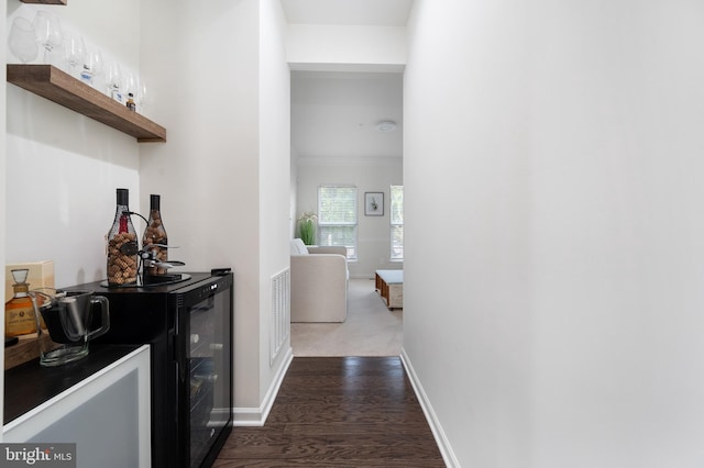 bar with ornamental molding, beverage cooler, and dark hardwood / wood-style flooring