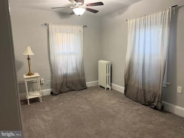 carpeted empty room with baseboards, radiator heating unit, and ceiling fan