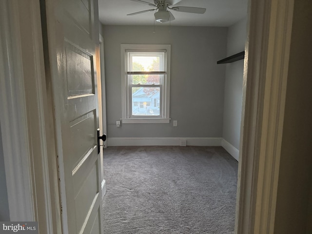 carpeted empty room featuring baseboards and ceiling fan