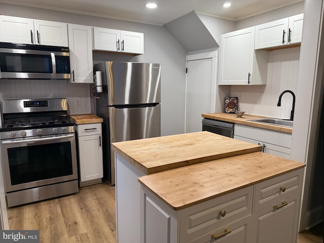 kitchen with a sink, recessed lighting, butcher block countertops, and appliances with stainless steel finishes