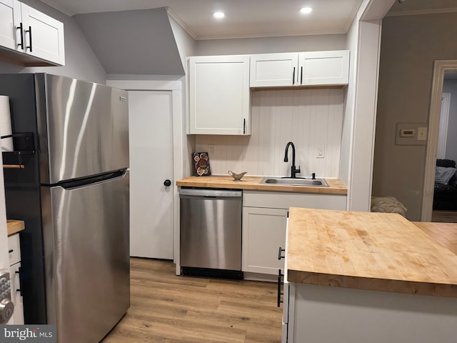kitchen featuring stainless steel appliances, wooden counters, light wood-type flooring, and a sink
