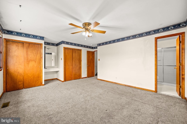 unfurnished bedroom with light carpet, multiple closets, and ensuite bathroom