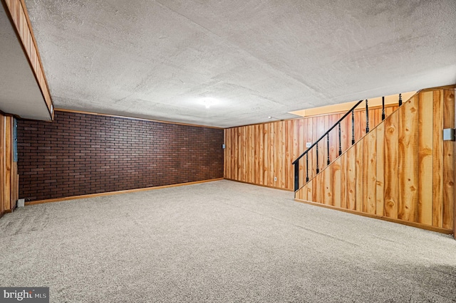 basement with brick wall, light carpet, a textured ceiling, and wood walls