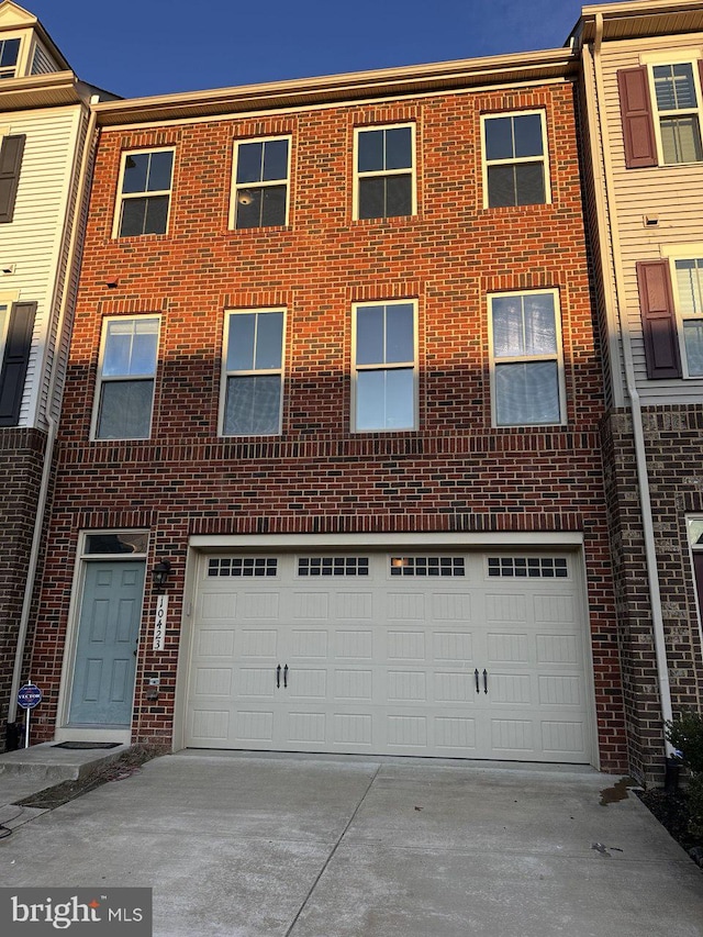 townhome / multi-family property with a garage, driveway, and brick siding