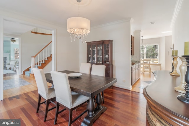 dining area with baseboards, an inviting chandelier, dark wood-style flooring, stairs, and crown molding