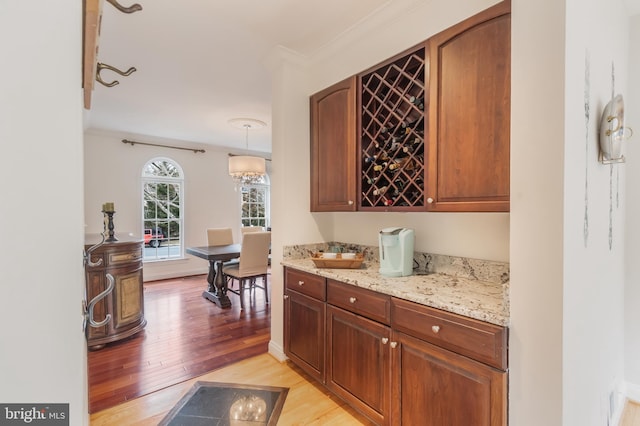 bar featuring light wood-type flooring and ornamental molding