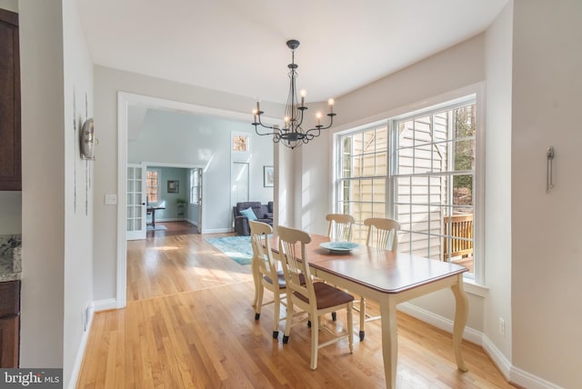 dining area featuring french doors, baseboards, a chandelier, and light wood finished floors