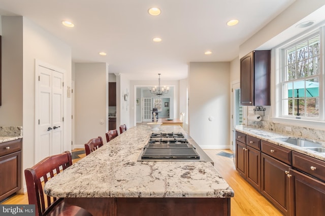 kitchen with an inviting chandelier, light wood-style flooring, recessed lighting, stainless steel gas stovetop, and a center island