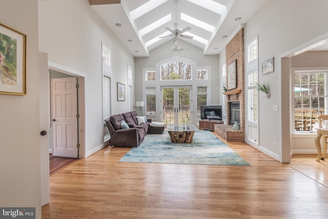 living area featuring a skylight, a healthy amount of sunlight, light wood finished floors, and high vaulted ceiling