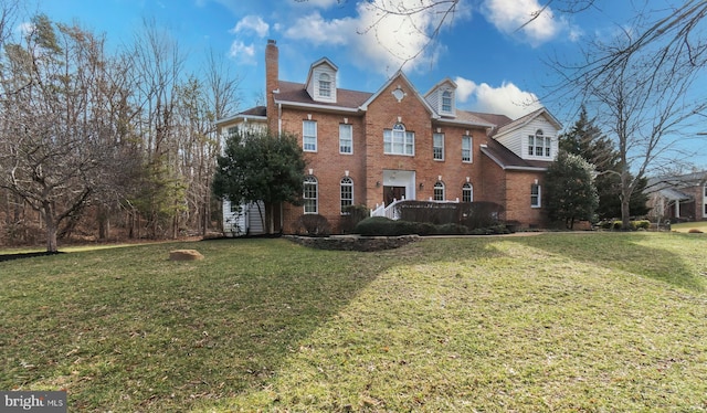 view of front of home with a front lawn, brick siding, and a chimney