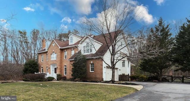 view of front of home featuring driveway, fence, a front yard, an attached garage, and brick siding