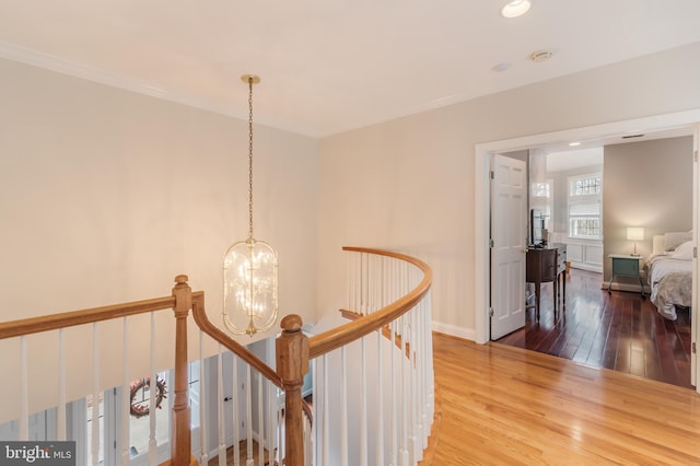 hall featuring an inviting chandelier, an upstairs landing, baseboards, and wood-type flooring