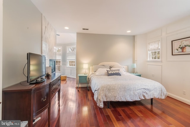 bedroom with recessed lighting, visible vents, dark wood-style floors, and a decorative wall