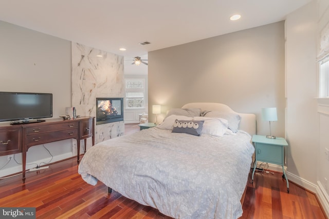 bedroom featuring visible vents, baseboards, a multi sided fireplace, recessed lighting, and wood finished floors