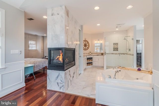 bathroom featuring visible vents, wood finished floors, ensuite bath, a tile shower, and a tile fireplace