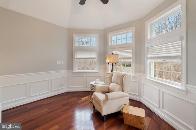 sitting room with dark wood finished floors, vaulted ceiling, ceiling fan, and wainscoting