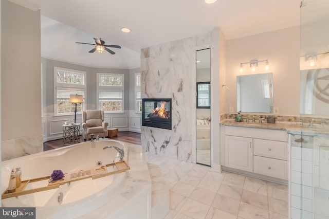 bathroom with a tiled fireplace, a wainscoted wall, a whirlpool tub, recessed lighting, and vanity