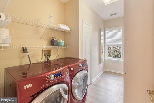 laundry area featuring visible vents, washer and dryer, wood finished floors, baseboards, and laundry area