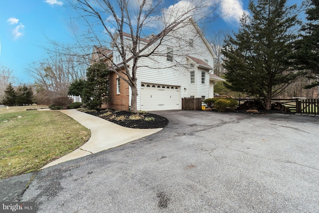 view of side of home featuring a lawn, a garage, and driveway