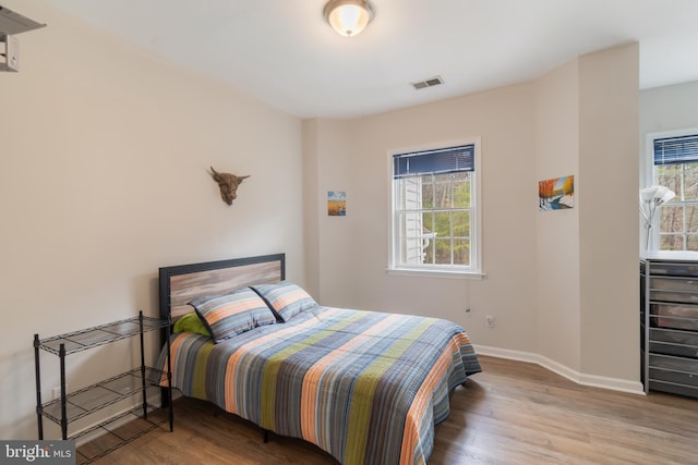 bedroom featuring visible vents, baseboards, and wood finished floors