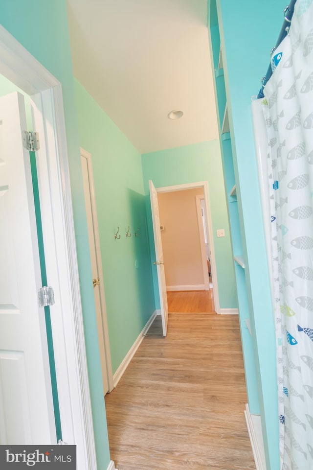 hallway featuring baseboards and light wood-type flooring