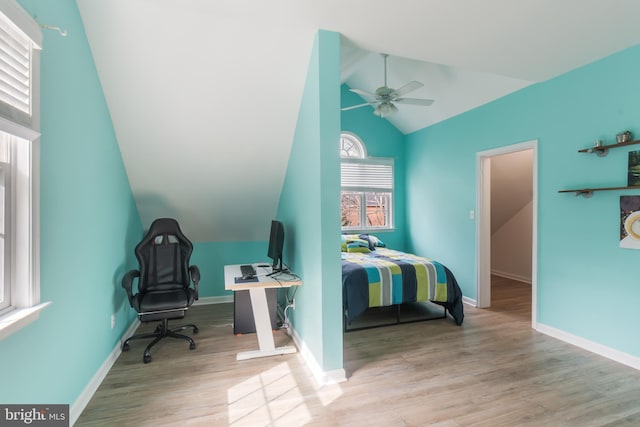 bedroom with a ceiling fan, vaulted ceiling, wood finished floors, and baseboards