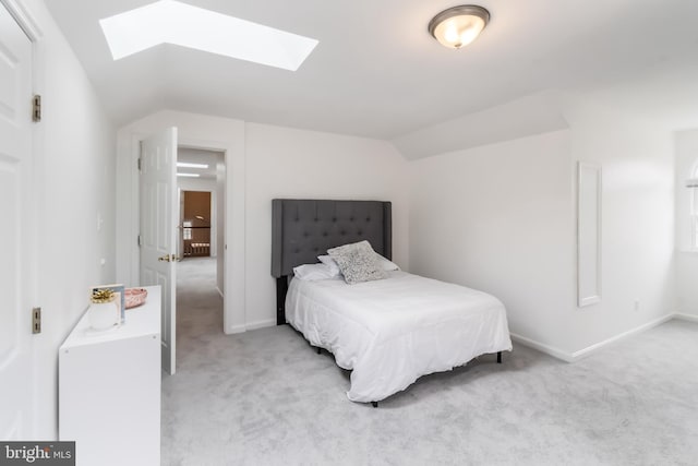 carpeted bedroom featuring lofted ceiling with skylight and baseboards