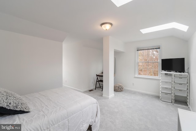 carpeted bedroom with vaulted ceiling with skylight and baseboards