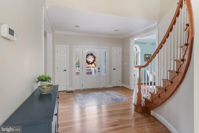 foyer entrance featuring stairs, baseboards, crown molding, and light wood-style floors