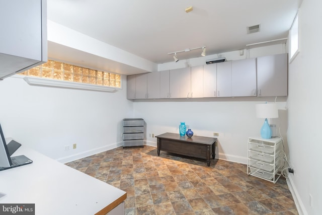 home office featuring track lighting, stone finish floor, and baseboards