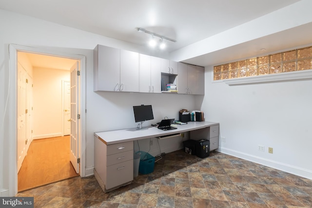 office area with track lighting, baseboards, and stone finish flooring