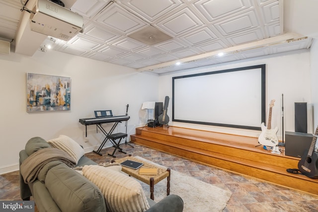 cinema room featuring an ornate ceiling, stone finish flooring, and baseboards