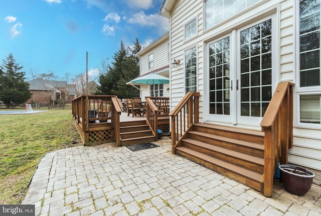 deck with french doors, a patio, a lawn, and entry steps