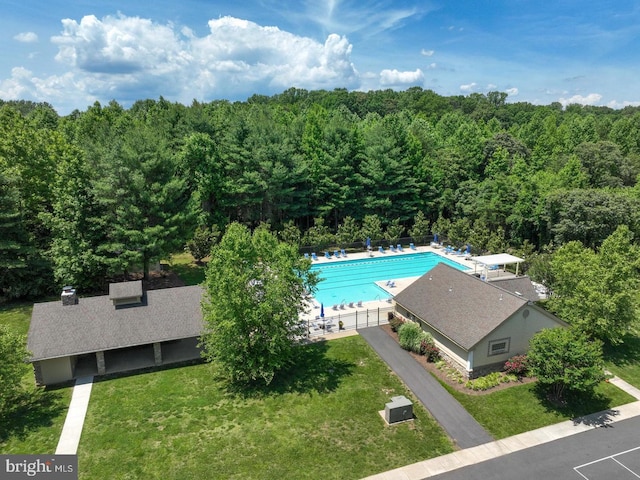 pool with central air condition unit, a lawn, and a forest view