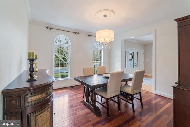 dining area featuring dark wood finished floors, crown molding, and baseboards