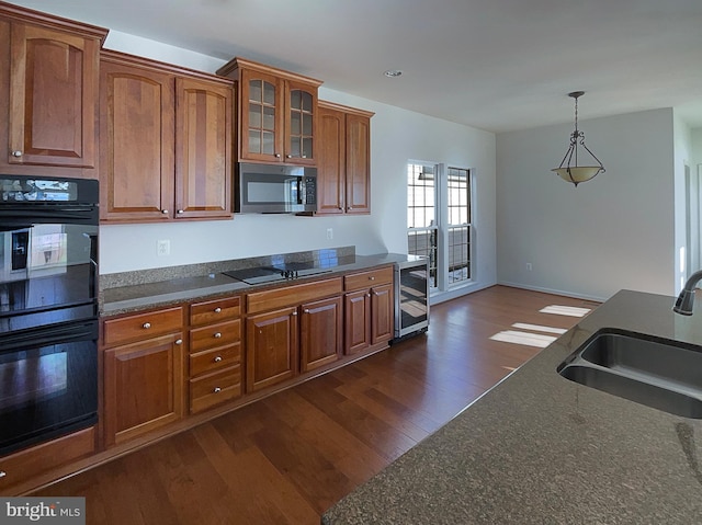 kitchen with pendant lighting, sink, dark hardwood / wood-style floors, black appliances, and beverage cooler