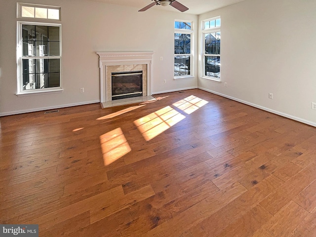 unfurnished living room featuring hardwood / wood-style flooring, a premium fireplace, and ceiling fan