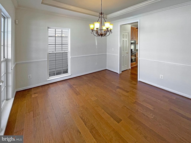 unfurnished dining area featuring dark hardwood / wood-style flooring, a tray ceiling, crown molding, and a chandelier