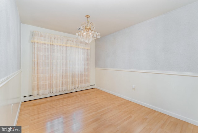 unfurnished room featuring wood-type flooring, a chandelier, and baseboard heating