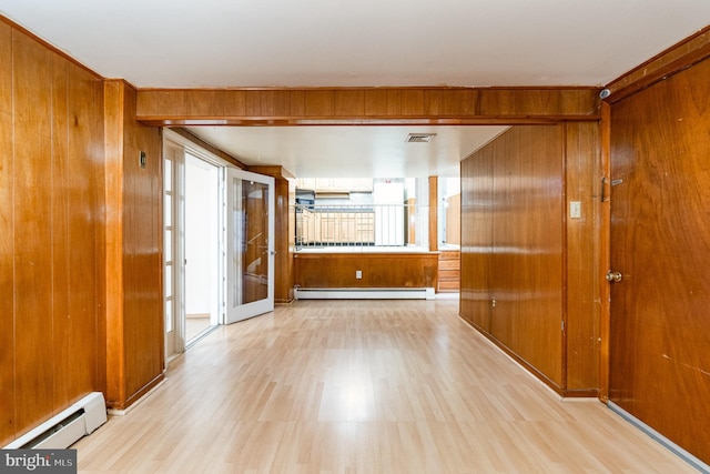 interior space featuring a wealth of natural light, a baseboard radiator, and wooden walls