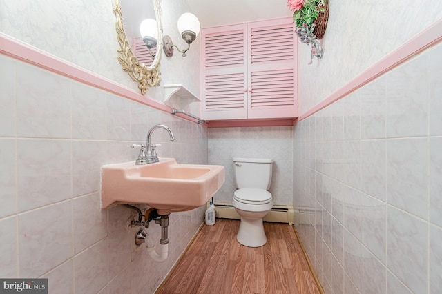 bathroom with tile walls, a baseboard heating unit, hardwood / wood-style flooring, and toilet